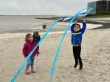 Kinderen spelen met een vlieger op het strand.