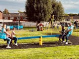 Kinderen spelen met begeleiders op de wipwap in de speeltuin.