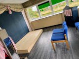 Theaterkamer met blauwe stoelen en podium.
