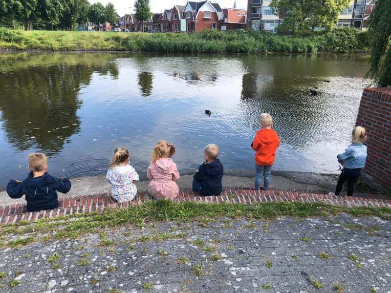 Kinderen zitten aan de kant van een meer.
