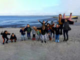 Kinderen en begeleiders springen in de lucht op het strand.